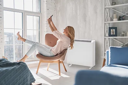 Woman leisurely sat in front of an Elnur PROSSH Storage Heater